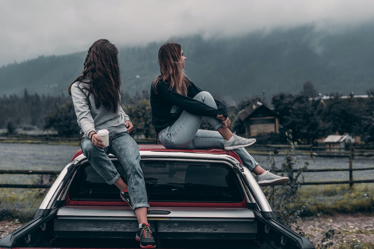 Two women sitting on a car roof