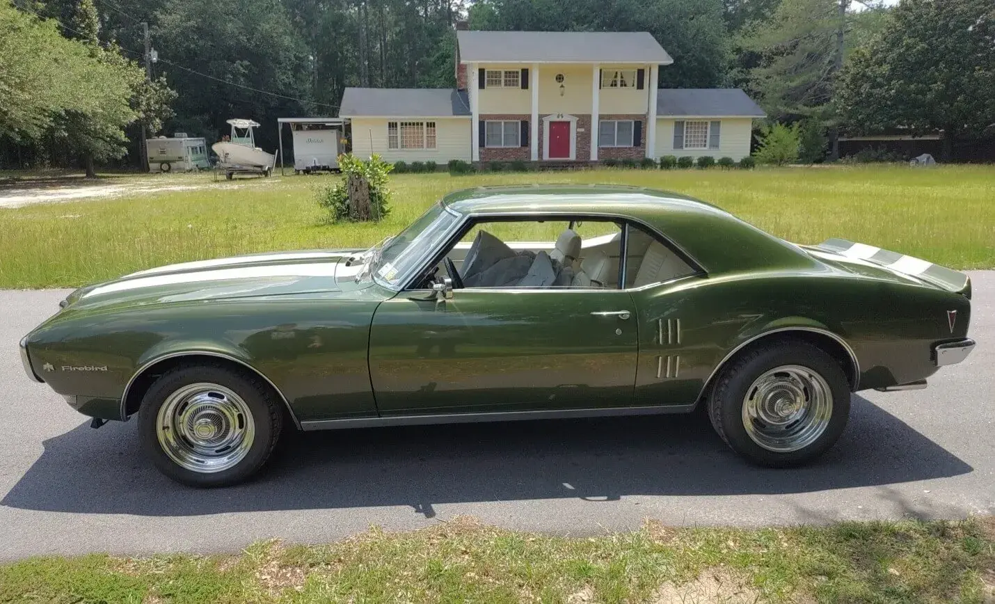 Green firebird parked in front of a house