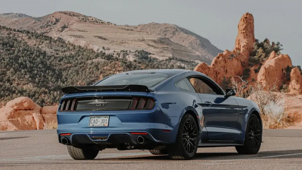 Blue Ford Mustang driving among mountains