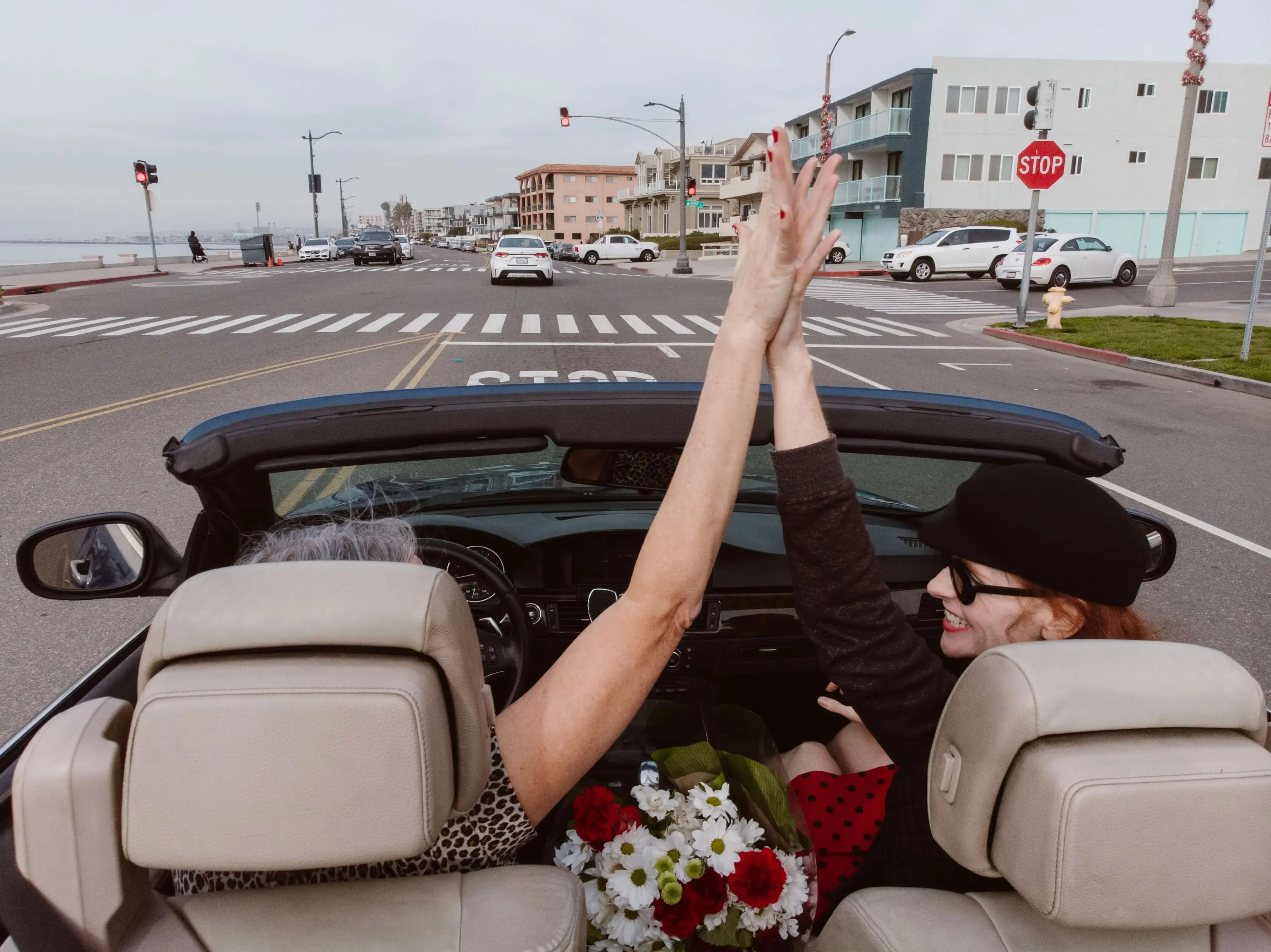 Two women giving high five in a convertible vehicle in California