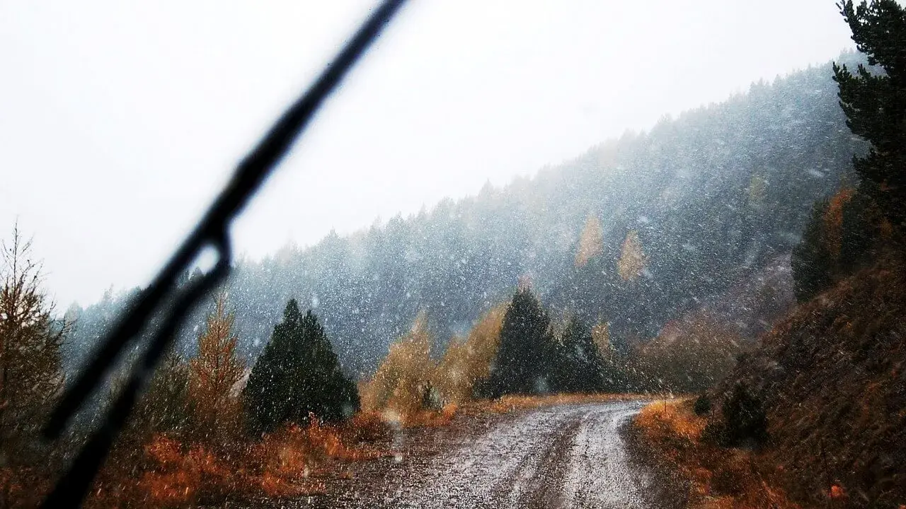 A mountain winter road thorugh a car's window