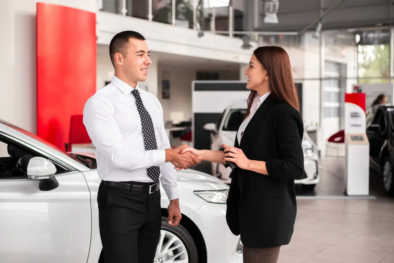 Man and woman shake hands on a successfully sold car Man and woman shake hands on a successfully sold car