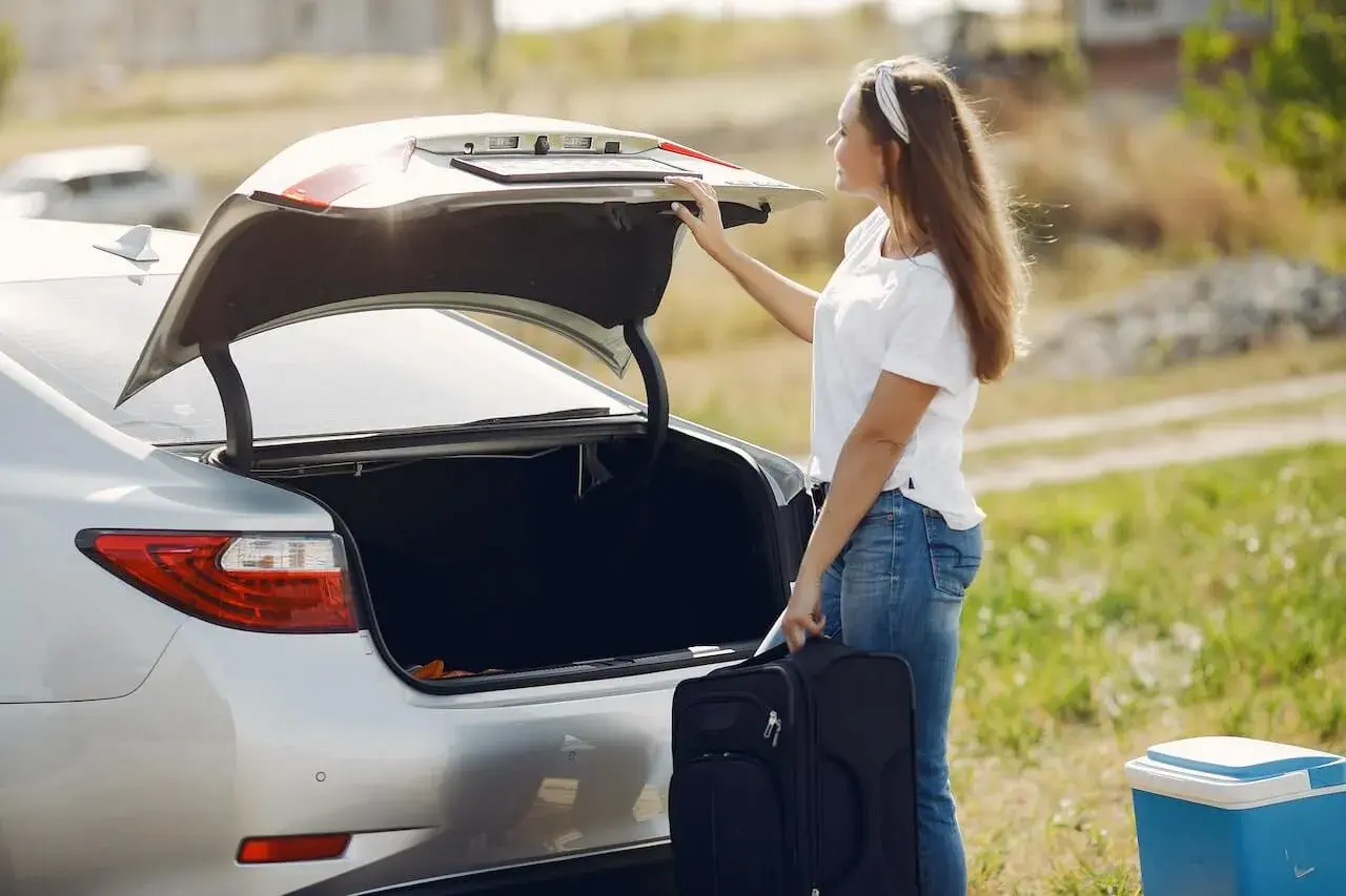 A woman placing a suitcase in the the boot of the car
